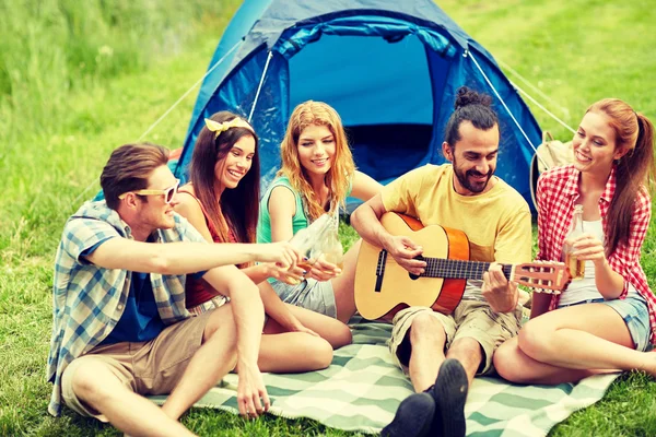 Amigos felizes com bebidas e guitarra no acampamento — Fotografia de Stock