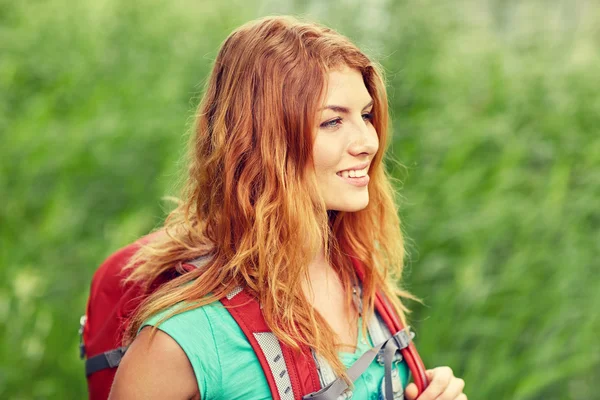 Leende ung kvinna med ryggsäck vandring i skogen — Stockfoto