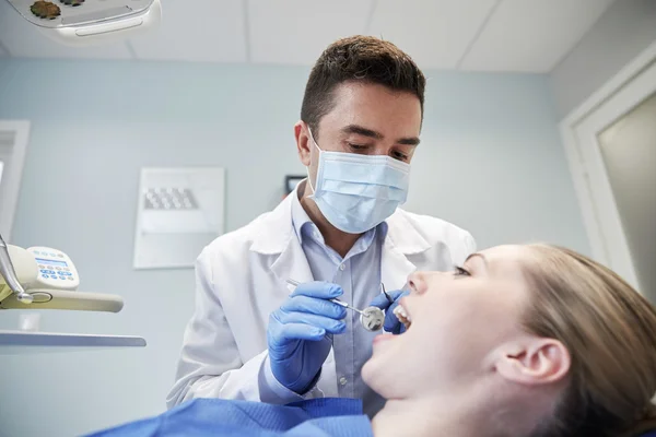 男牙医在检查女病人牙齿的面具 — 图库照片