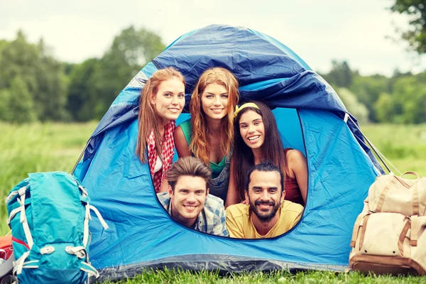 Happy friends with backpacks in tent at camping — Stock Photo, Image