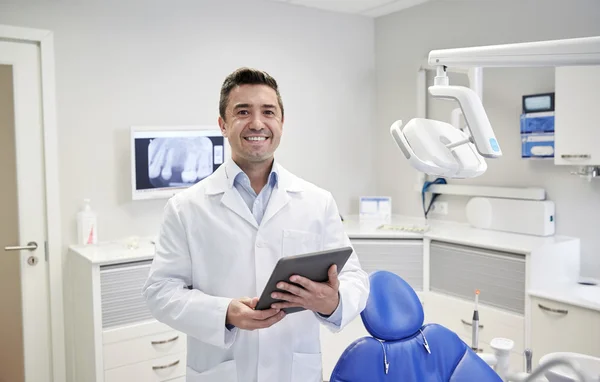 Dentista masculino feliz com tablet pc na clínica odontológica — Fotografia de Stock