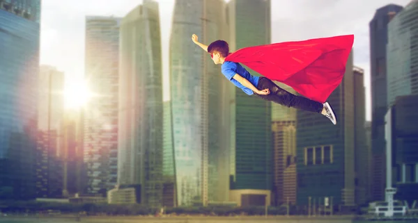 Niño en capa de superhéroe y máscara volando sobre la ciudad —  Fotos de Stock