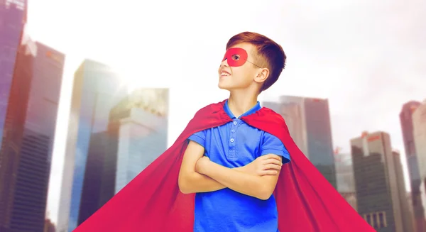 Boy v červené superhrdina mys a maska nad městem — Stock fotografie