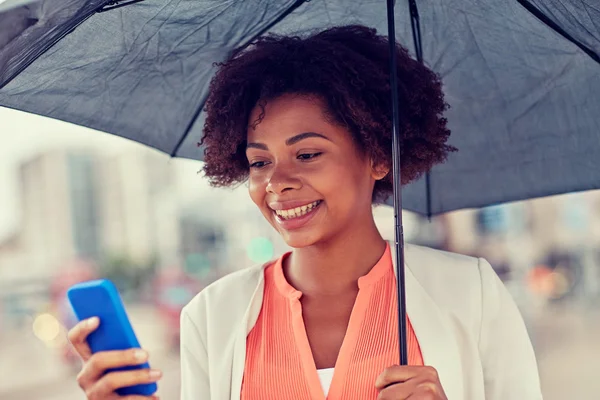 Business woman with umbrella texting on smartphone Стоковое Изображение