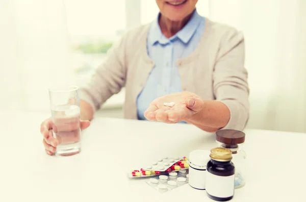 Happy senior woman with water and pills at home — Stock Photo, Image