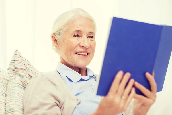 Gelukkig lachend senior vrouw lezing boek thuis — Stockfoto