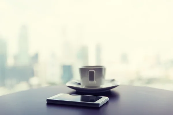 Close up de smartphone e xícara de café na mesa — Fotografia de Stock