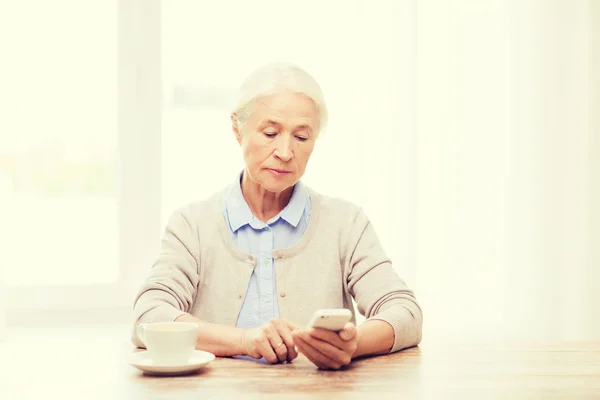 Starsza kobieta ze smartfonem smsowanie w domu — Zdjęcie stockowe