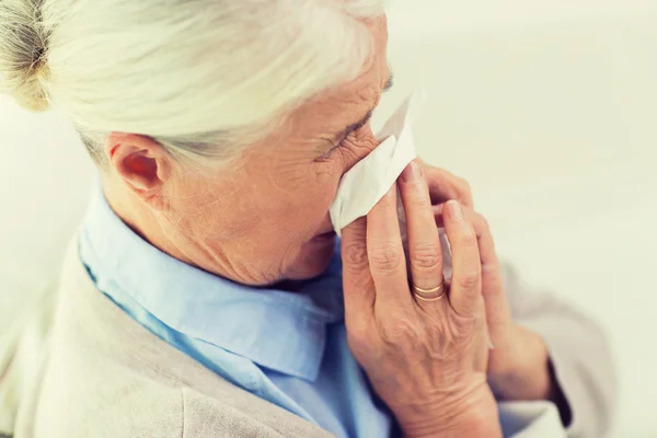 Wanita senior yang sakit meniup hidung ke serbet kertas — Stok Foto