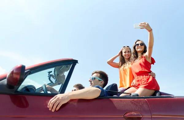 Amigos conduciendo en coche cabriolet y tomando selfie —  Fotos de Stock