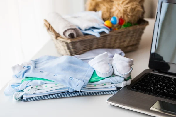 Close up de roupas de bebê, brinquedos e laptop — Fotografia de Stock