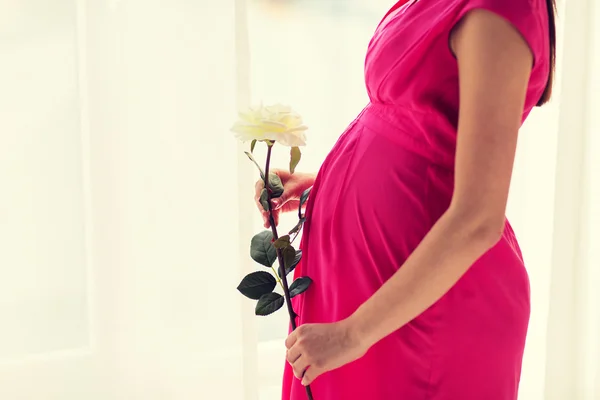 Happy pregnant woman with rose flower at home — Stock Photo, Image