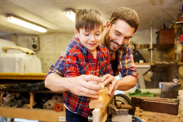 Father and son with plane shaving wood at workshop — Stock Photo, Image