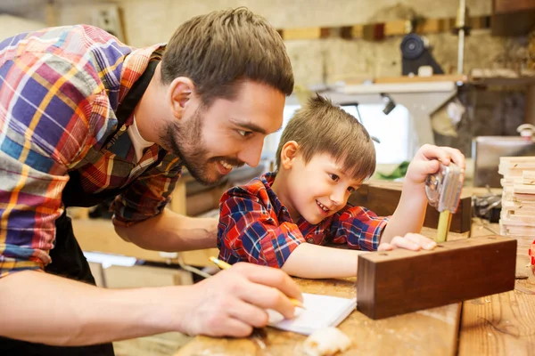 Dad and son with ruler measuring plank at workshop — Stock Photo, Image