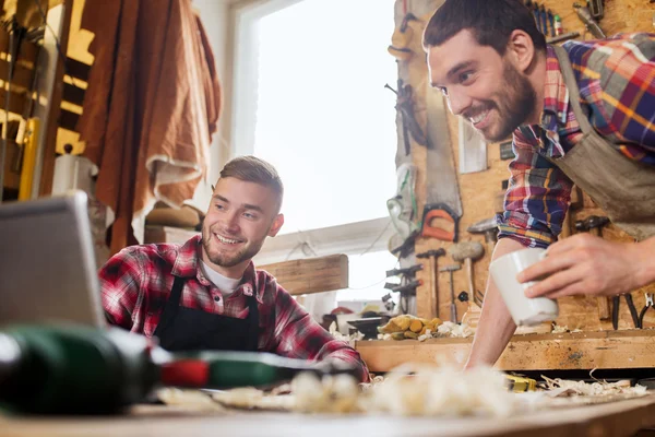 Dos carpinteros sonrientes con portátil en el taller —  Fotos de Stock