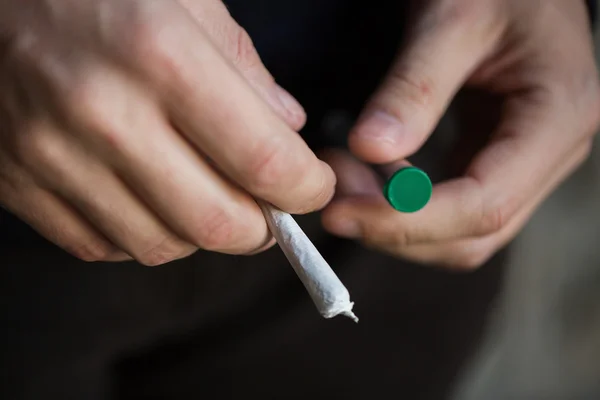 Close-up de mãos viciadas com tubo comum de maconha — Fotografia de Stock