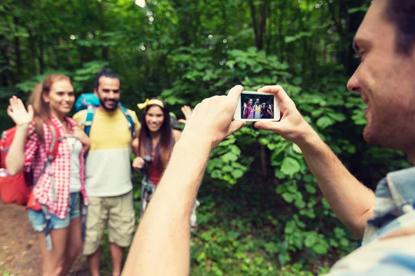 Happy man photographing friends by smartphone — Stok fotoğraf