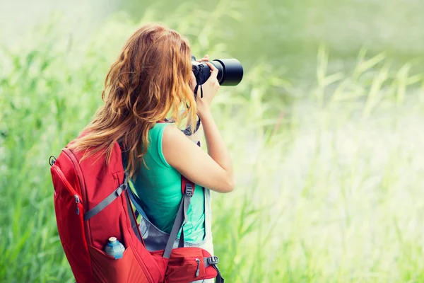 Mladá žena s batohem a fotoaparát venku — Stock fotografie