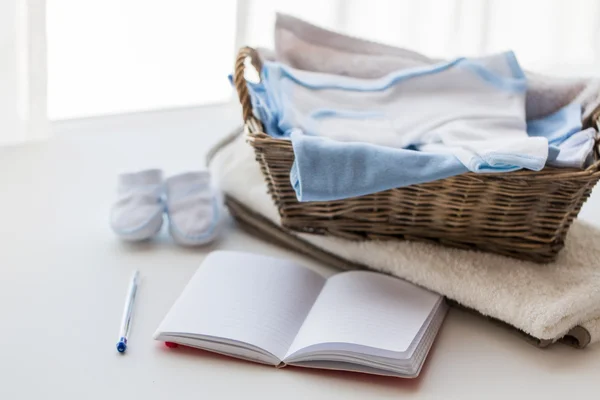 Primo piano di vestiti per bambini per neonato e notebook — Foto Stock