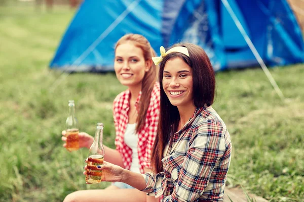 Happy young women with tent and drinks at campsite — Stock Photo, Image