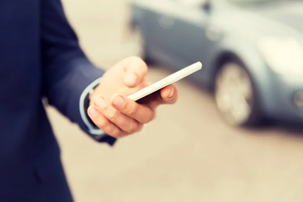 Close-up de mão homem com smartphone e carro — Fotografia de Stock