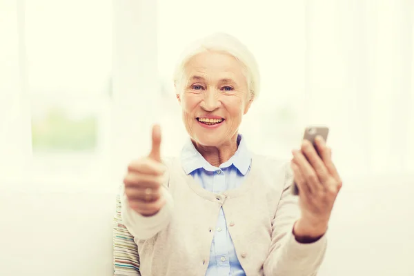Пожилая женщина со смартфоном показывает большие пальцы вверх — стоковое фото