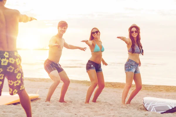 Smiling friends in sunglasses with surfs on beach — Stock Photo, Image