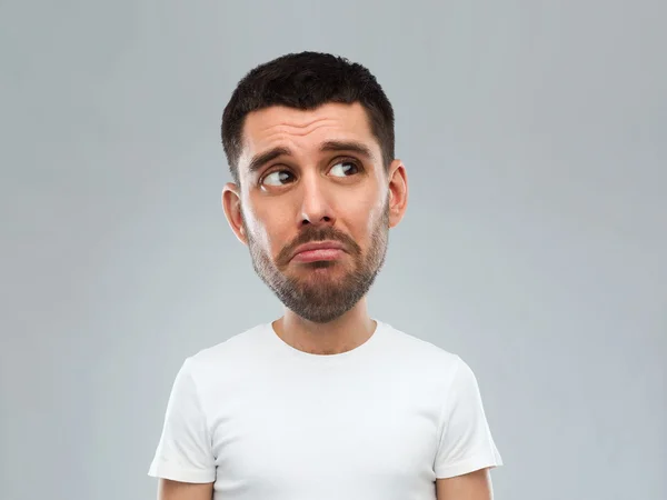 Unhappy young man over gray background — Stock Photo, Image