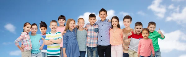Grupp glada barn kramas över blå himmel — Stockfoto