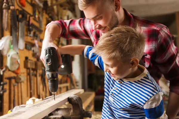 Отец и сын с дрелью работают в мастерской — стоковое фото