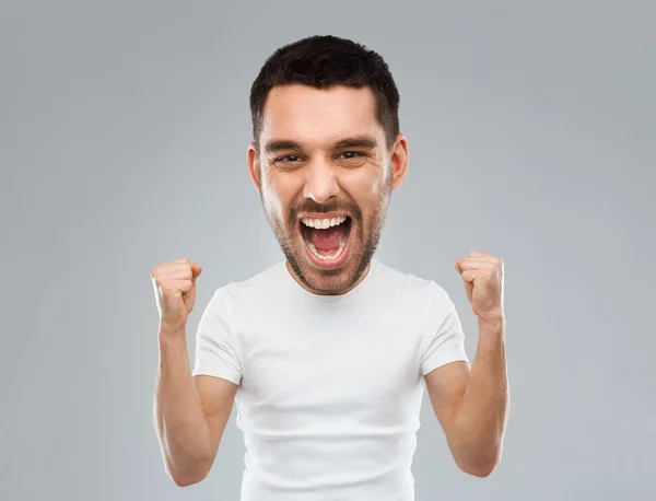 Joven celebrando la victoria sobre gris —  Fotos de Stock