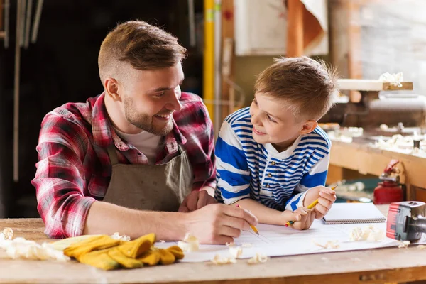 Happy father and son with blueprint at workshop — Stock Photo, Image