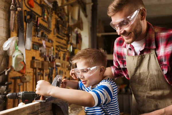 Father and son with plane shaving wood at workshop — Stock Photo, Image