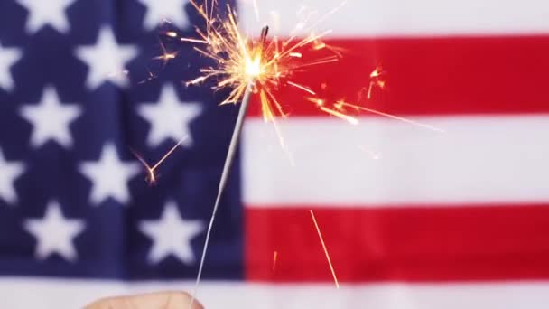 Close up de mão com sparkler sobre bandeira americana — Vídeo de Stock