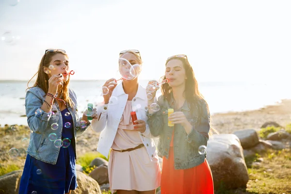 Jonge vrouwen of meisjes blazen van zeepbellen op strand — Stockfoto