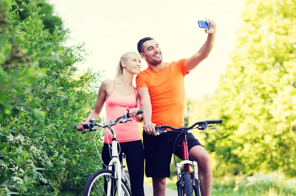 Пара с велосипедом делает селфи на смартфоне — стоковое фото