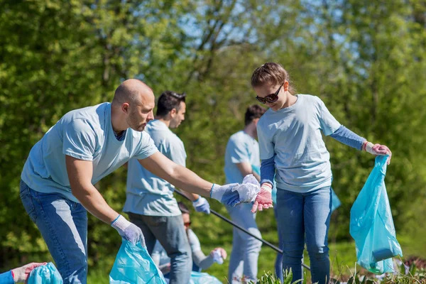 Relawan dengan kantong sampah membersihkan area taman — Stok Foto