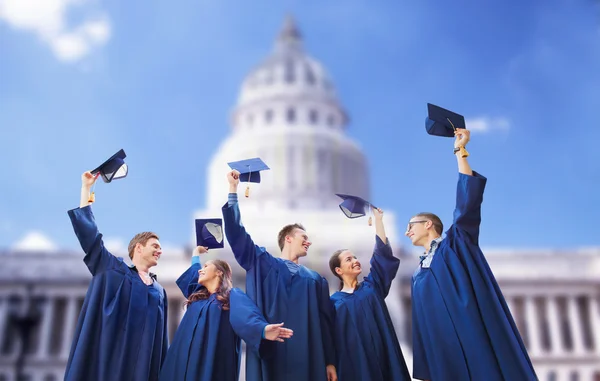 Grupp av glada studenter vinka mortarboards — Stockfoto