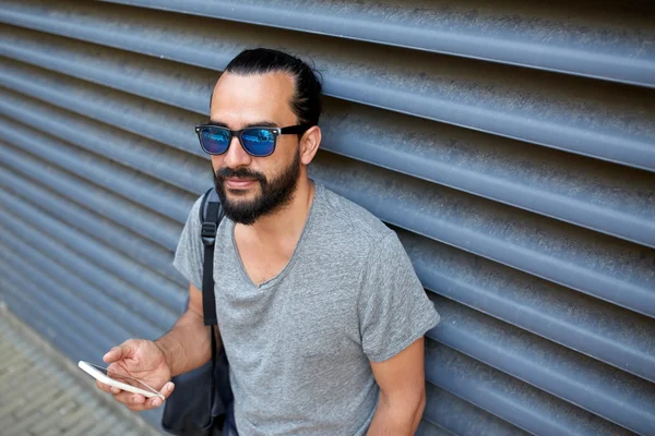 Homem com mochila mensagens de texto no smartphone na cidade — Fotografia de Stock