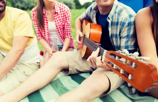 Amigos felizes com bebidas e guitarra no acampamento — Fotografia de Stock