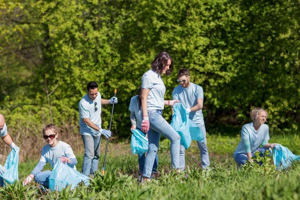 Voluntários com sacos de lixo área do parque de limpeza — Fotografia de Stock