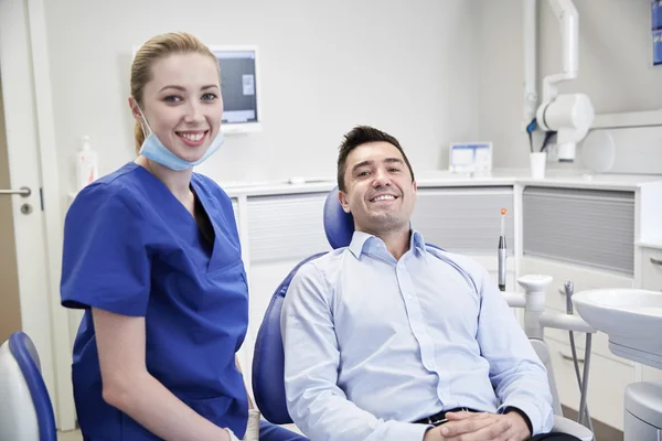 Gelukkig vrouwelijke tandarts met man patiënt bij kliniek Stockafbeelding