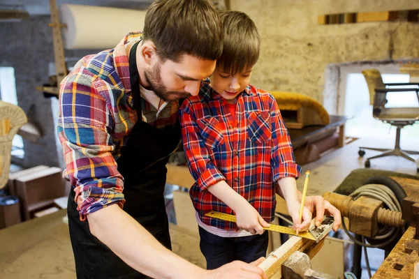 Padre e hijo con regla miden madera en el taller —  Fotos de Stock