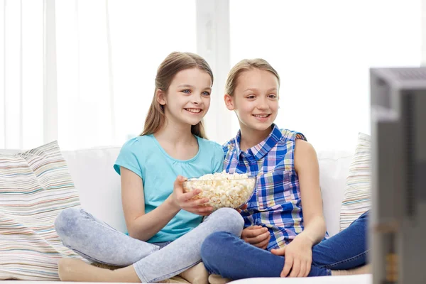 Счастливые девочки с кукурузой смотрят телевизор дома — стоковое фото
