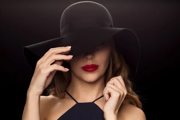 Schöne Frau mit schwarzem Hut vor dunklem Hintergrund — Stockfoto