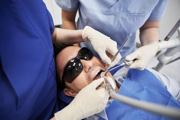 Mãos dentista tratamento de dentes do paciente masculino — Fotografia de Stock