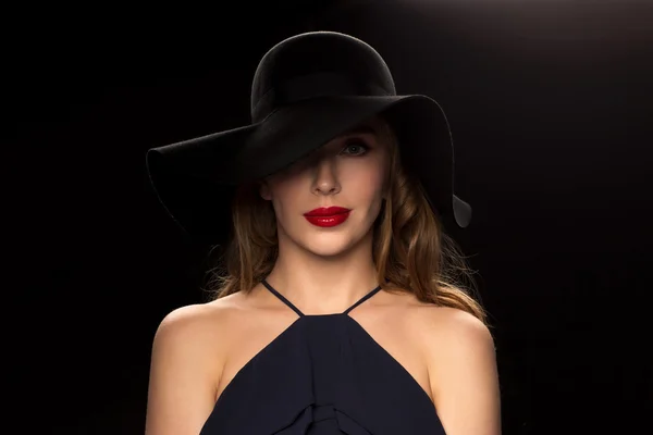 Beautiful woman in black hat over dark background — Stock Photo, Image