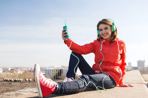 Gelukkig jonge vrouw met smartphone en hoofdtelefoons — Stockfoto