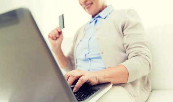 Oudere vrouw met laptop en creditcard thuis — Stockfoto