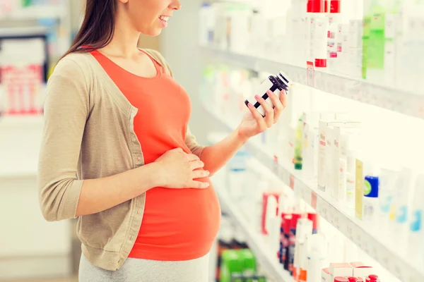 Gelukkig zwangere vrouw met medicatie bij apotheek — Stockfoto